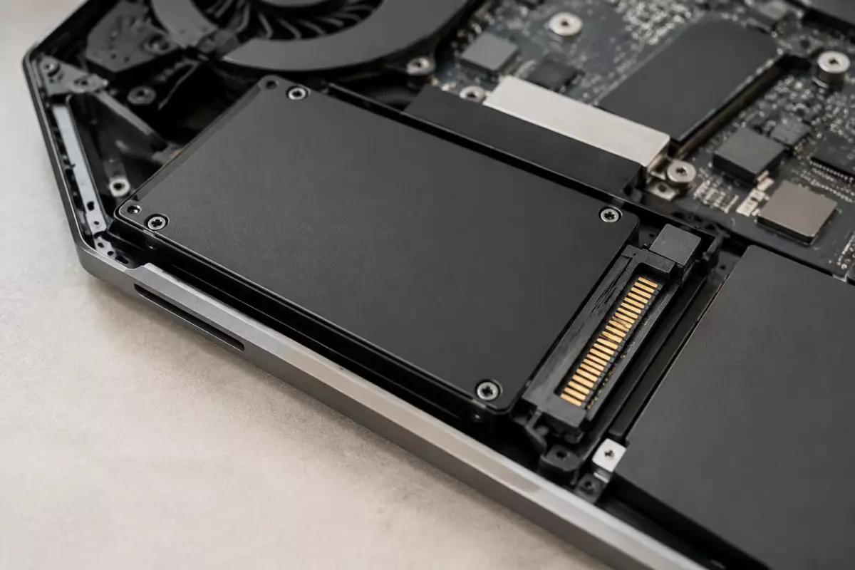 Крупный план компактного SSD-накопителя рядом с ноутбуком без маркировок и текстовых элементов