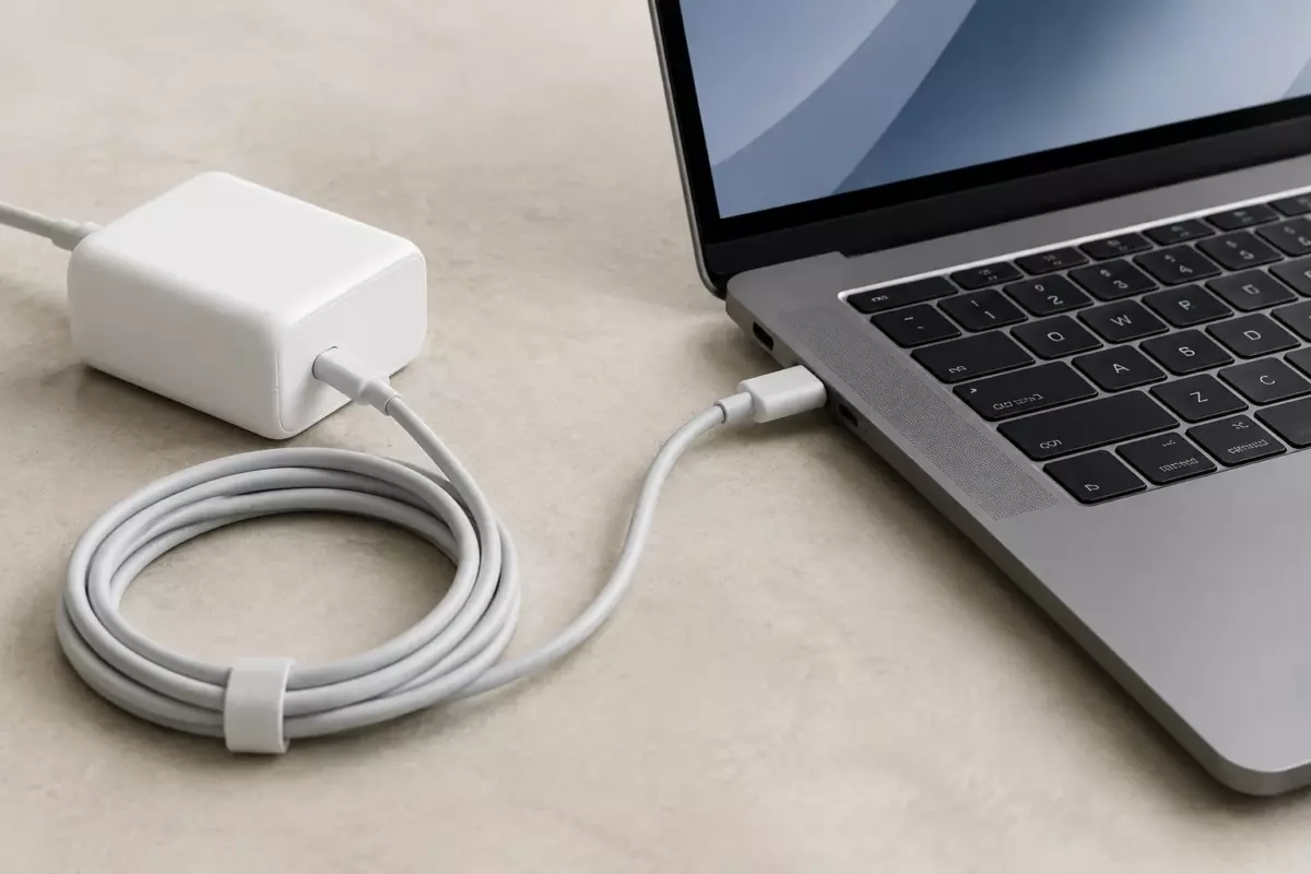 Ноутбук рядом с USB-C зарядным устройством и кабелем для проверки совместимости