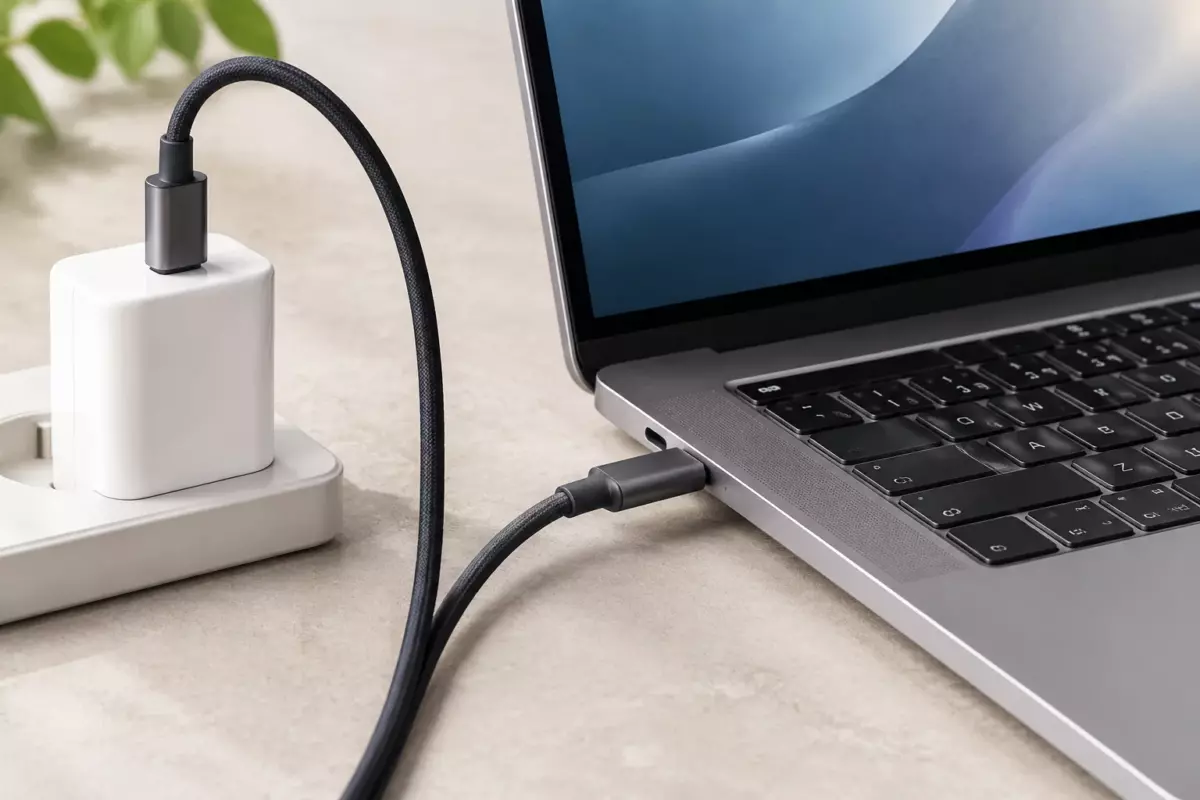 Ноутбук с USB-C кабелем и компактным блоком питания на нейтральной поверхности без брендов